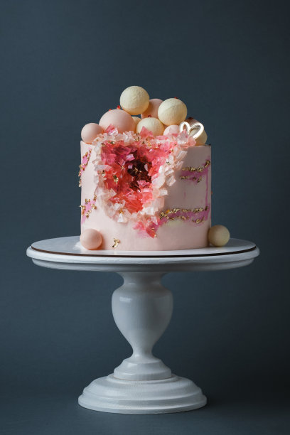 奢华的周年纪念蛋糕，粉红色奶油奶酪糖霜，深灰色背景上点缀着金色花瓣。情人节快乐。送给心爱女人的蛋糕，上面有红色和粉色的可食用水晶图片下载