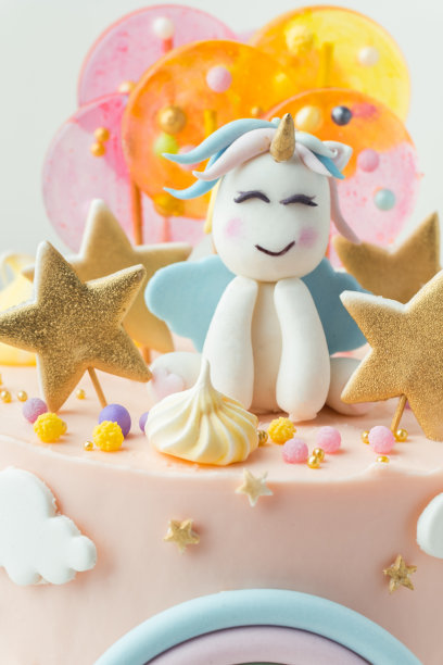 独角兽蛋糕，粉色奶油奶酪糖霜装饰乳脂彩虹，彩色焦糖糖果和独角兽形状的人在上面。白色背景上有一个小女孩的生日蛋糕图片下载