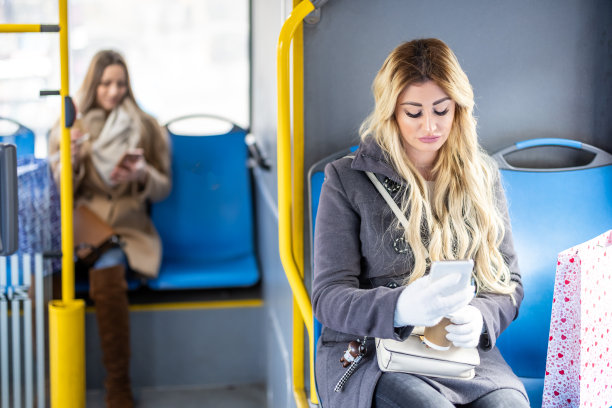 一个时髦的年轻女子坐在城市公交车上用手机。图片下载