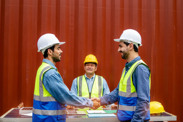 聪明的技术人员戴着安全帽和制服，有握手的团队合作理念图片下载