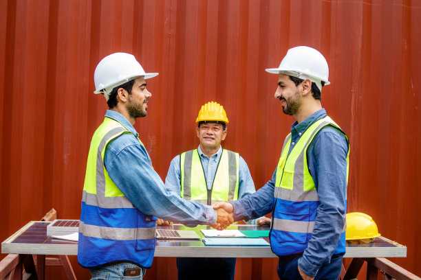 聪明的技术人员戴着安全帽和制服，有握手的团队合作理念图片下载