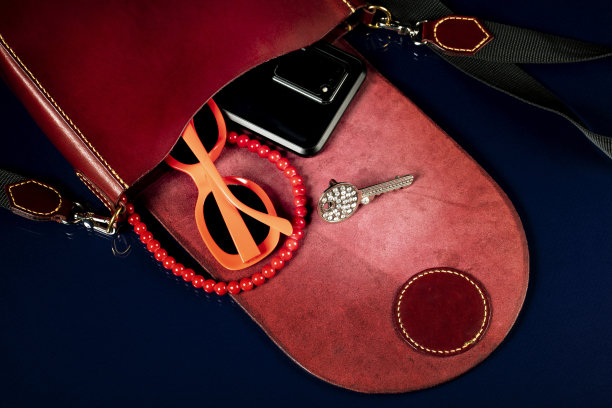 红色皮革包与女性的配件在一个黑暗的背景。图片下载