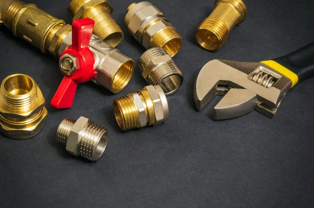维修或更换备件时，管道黄铜配件和可调节扳手在黑色背景上的特写图片下载