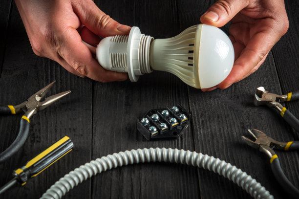 电工师傅打开灯泡。近距离的工人的手在桌面上的车间。免费广告位图片下载