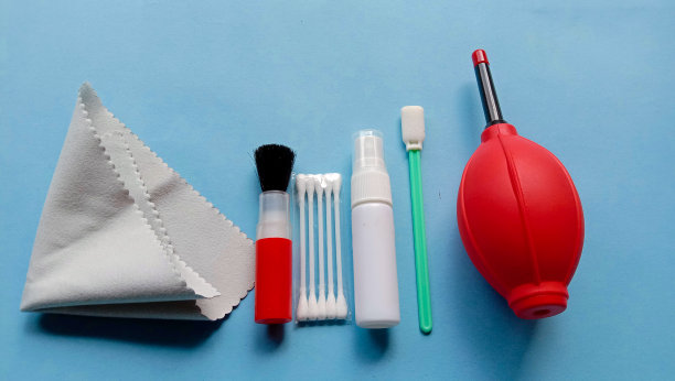 照片的相机清洁用品，如鼓风机，刷子，超纤维布，水喷雾在蓝色的背景图片下载