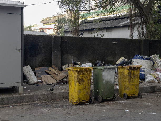 在人行道上的一个社区垃圾场，垃圾旁边有三个垃圾桶。图片下载