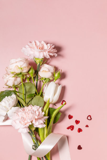 情人节贺卡，粉红色背景上有美丽的花朵和爱心。情人节、妇女节、婚礼、生日或母亲节。从上面看。副本的空间。图片下载