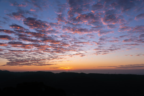 日落时浪漫壮观的城市景观。橙色天空中流动的云。图片下载