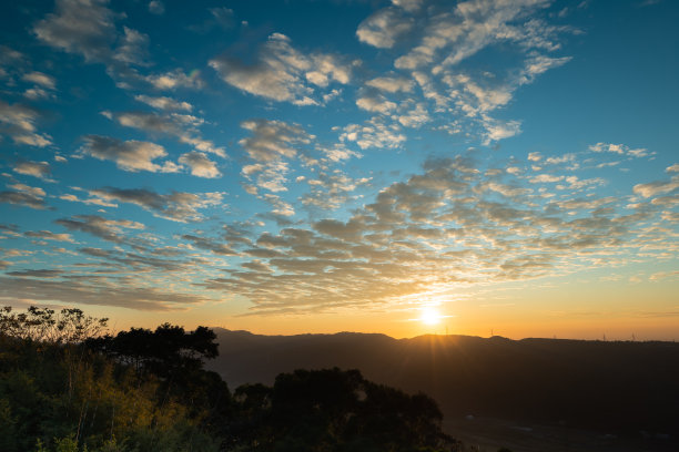 日落时浪漫壮观的城市景观。橙色天空中流动的云。图片下载