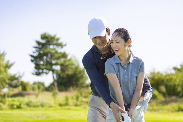 一个年轻的东亚男人和女人练习高尔夫在阳光明媚的白天高尔夫球场，教练和学生的股票照片图片下载