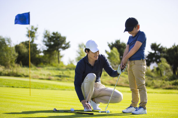 父亲和儿子在阳光明媚的高尔夫球场练习一杆进洞高尔夫球或开球，教练和学生，鼓励和赞扬-库存照片图片下载