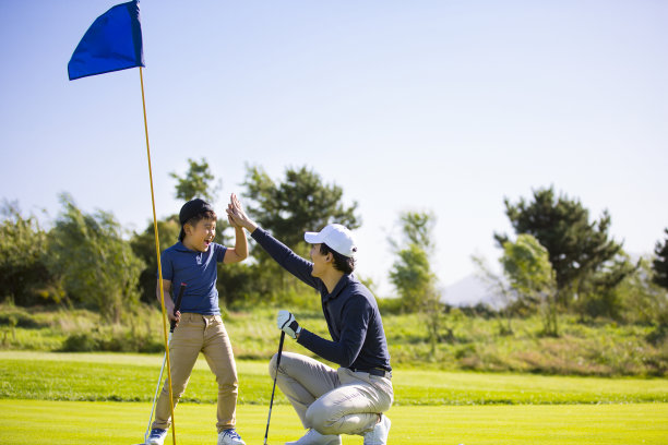 父亲和儿子在阳光明媚的高尔夫球场上击掌庆祝一杆进洞，教练和学生的照片图片下载