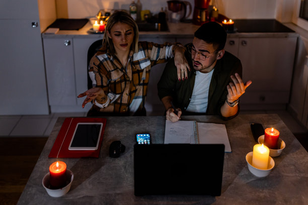 一对年轻夫妇在家里用笔记本电脑工作，遭遇电力危机。图片下载