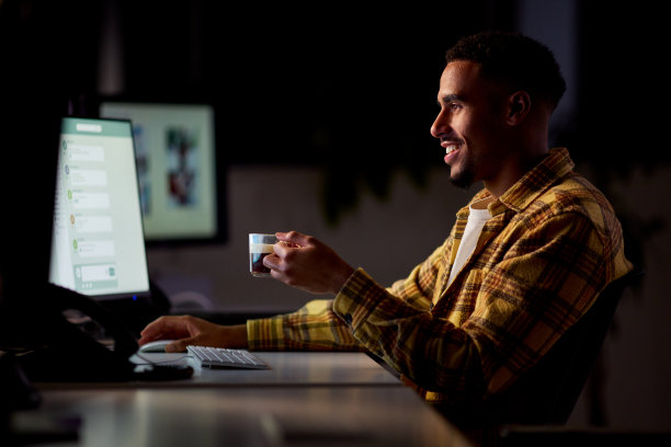 商人在办公室工作到很晚，喝咖啡时被电脑屏幕照亮了脸图片下载