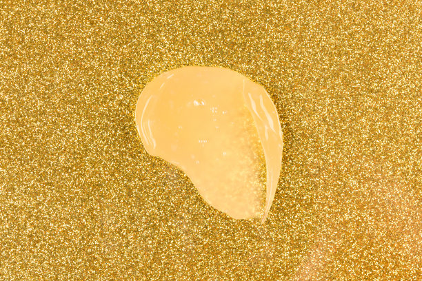 金色奶油污渍。生物金护肤产品，面部或眼霜涂抹在金色闪闪发光的背景。美容产品含金图片下载