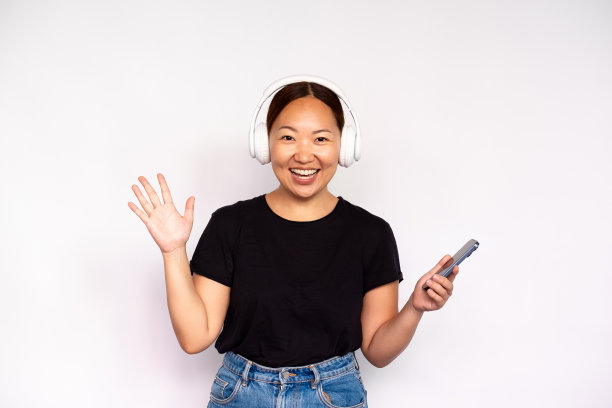 兴奋的年轻女子戴着耳机手持智能手机的肖像图片下载