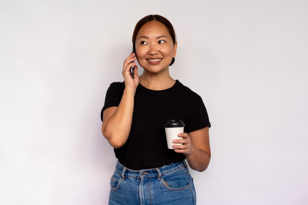 积极的年轻女子的肖像与咖啡讲电话图片下载