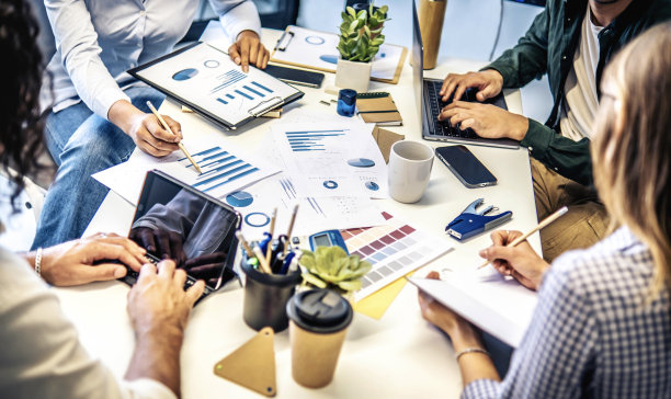 一群商务人士一起坐在办公桌前用电脑工作和交流-年轻的创意同事与新的启动项目一起工作-专注于手图片下载