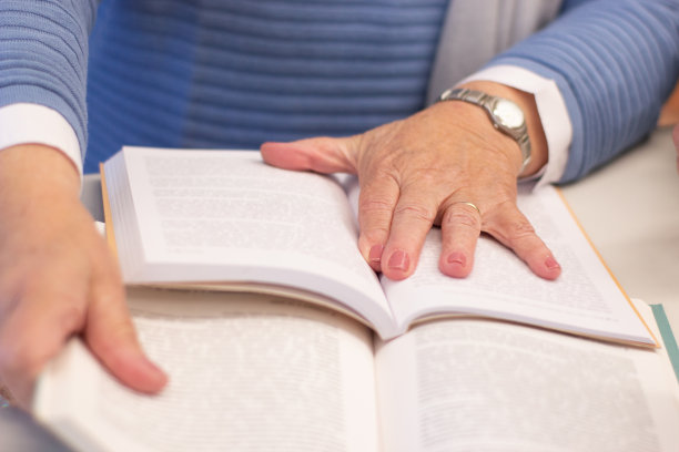 女性手放在打开的书上的特写图片下载