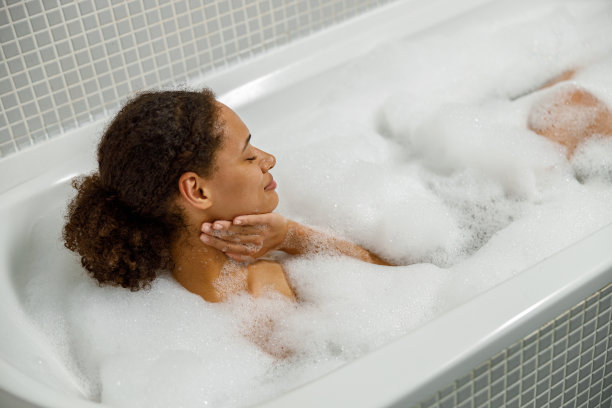 美丽的美国黑人妇女在浴缸里泡澡。水疗，健康和放松的概念图片下载