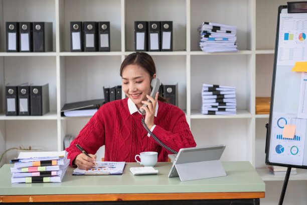 女商人拿着电话和她的主管交谈，用笔记本电脑向她的主管展示她的利润数据图表。图片下载
