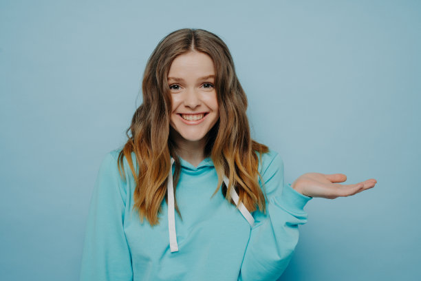 兴奋的年轻女孩耸肩与倾斜的手图片下载