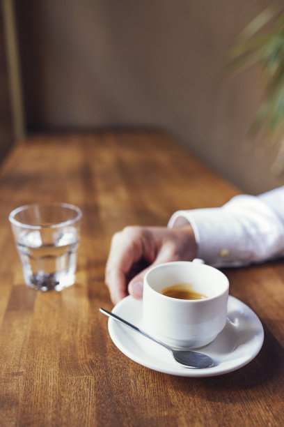 男性手握白色的浓咖啡杯。特写照片与选择性聚焦图片下载