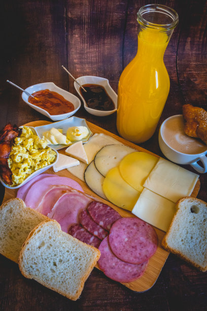 含面包、鸡蛋、培根、奶酪、萨拉米香肠、咖啡、果汁和果酱的早餐桌竖版照片图片下载