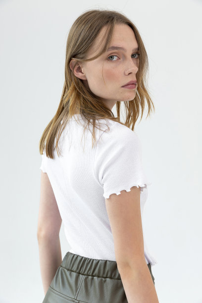 白色背景下，一个满脸雀斑的金发女孩穿着白色短袖上衣和绿色皮裤。图片下载