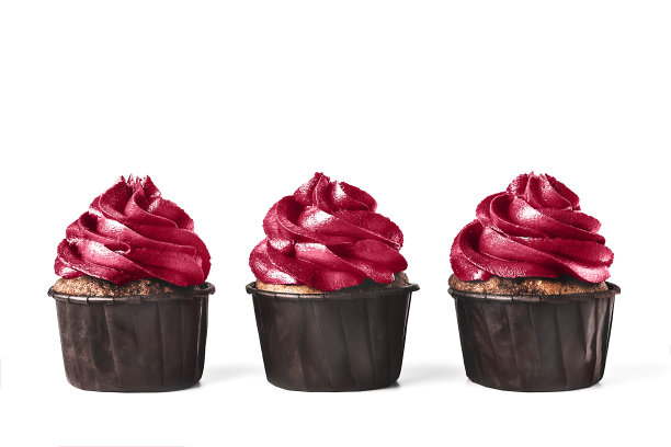 三个美味的巧克力纸杯蛋糕，白色背景上有糖霜。调成2023年流行的洋红色。图片下载