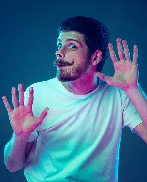 年轻英俊的男子，学生靠在透明玻璃孤立在黑暗的工作室背景。特写镜头。人类情感的概念，面部表情图片下载