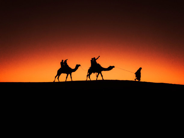 日落时分沙漠中商队的剪影图片下载