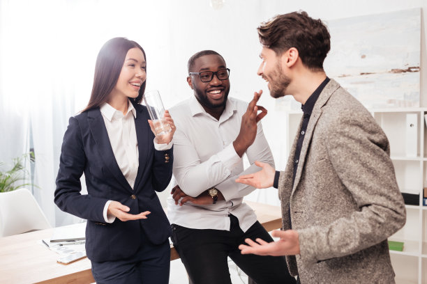 肖像快乐的跨国商人和女商人站在桌旁愉快地交谈，而在办公室一起孤立图片下载