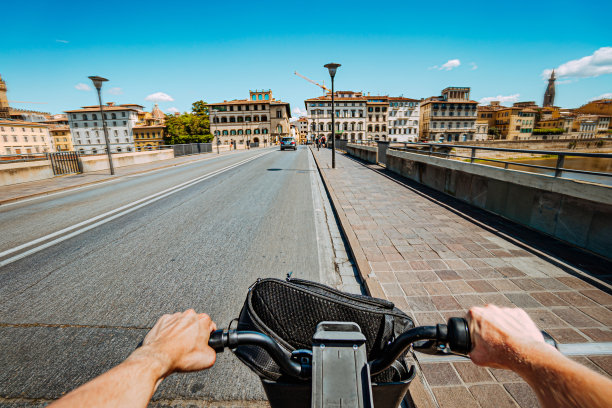“POV”视角图片，下午晚些时候骑着城市共享电动自行车穿过意大利佛罗伦萨的维奇奥桥图片下载
