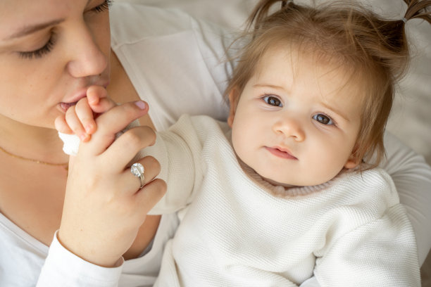 年轻疲惫的母亲和女婴在卧室看着相机的特写肖像。照顾孩子，家庭生活规律，健康的生活方式。筋疲力尽的女人要照顾孩子和家务。图片下载