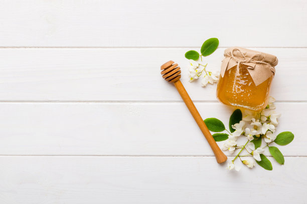 蜂蜜罐与金合欢花和叶子。新鲜蜂蜜顶部视图平铺图片下载