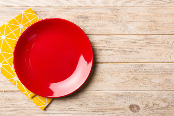 俯视图上的彩色背景空圆形红色盘子桌布上的食物。在餐巾纸上空出盘子，为你的设计留出空间图片下载