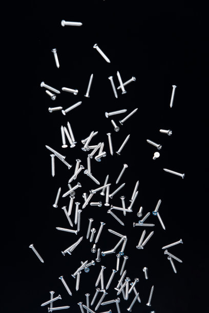 钉子飞在半空中。许多组螺丝钉短长金属落作为施工工具。黑色背景隔离。新螺丝起子钉子掉落，拆箱钢五金件图片下载