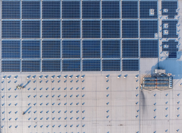 大型太阳能电池板阵列农场在一个商业配送仓库建筑自上而下图片下载