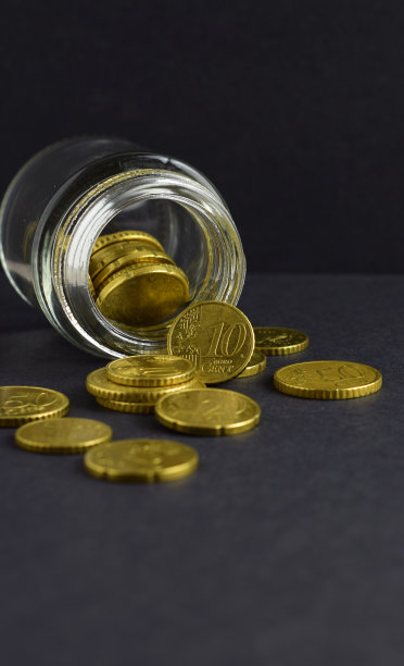 垂直拍摄的欧元硬币从罐子里溢出。图片下载