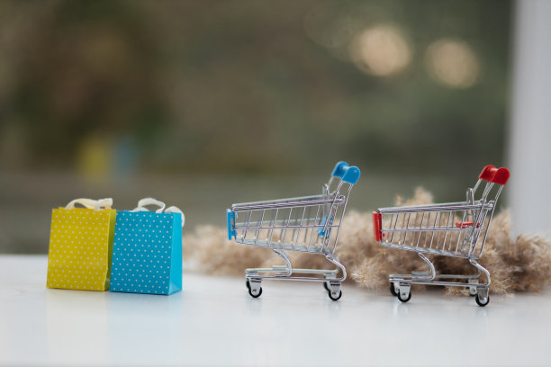迷你购物车在木制模拟在模糊的绿色花园在一天中午光，网上购物的概念形象。图片下载