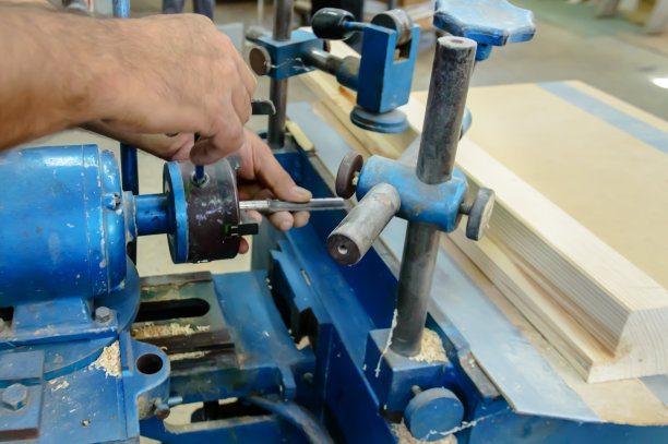 一个年轻的木匠正在工作场所分析冲孔机。图片下载