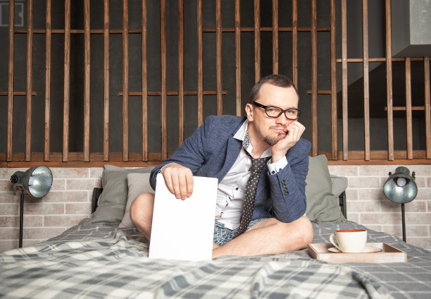 无聊的男人穿着西装和内裤在家上网坐在床上工作图片下载