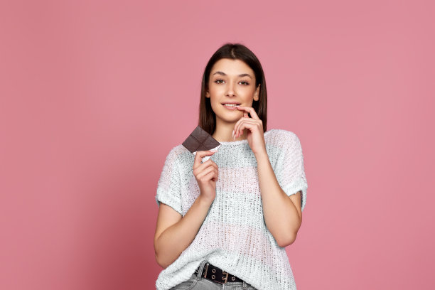 快乐的微笑女孩在毛衣拿着巧克力棒图片下载