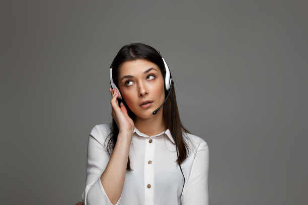 戴着耳机的友好微笑的女子正在网上咨询客户。图片下载