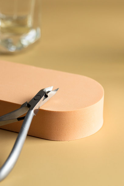 平台上的美甲工具角质层剪钳以米色为背景，为现代美甲沙龙的理念。图片下载