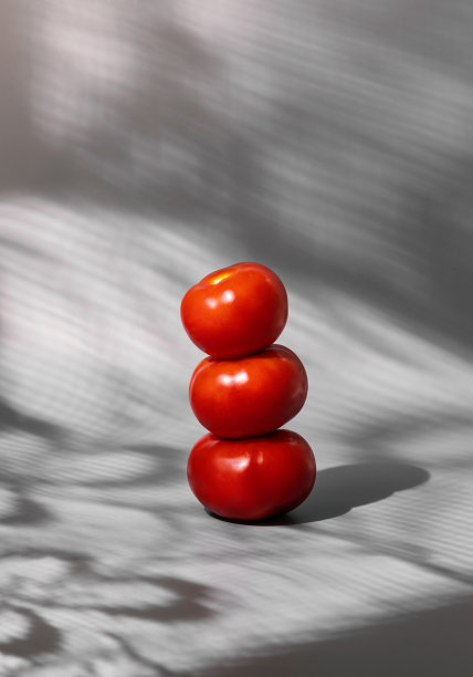 垂直的西红柿堆在灰色的背景上，阴影来自窗户和窗帘。抽象艺术美食照片图片下载