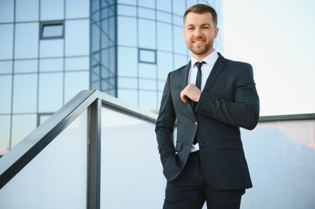 现代的商人。自信的年轻人穿着全套西装，站在户外，放眼望去，背景是城市风景图片下载