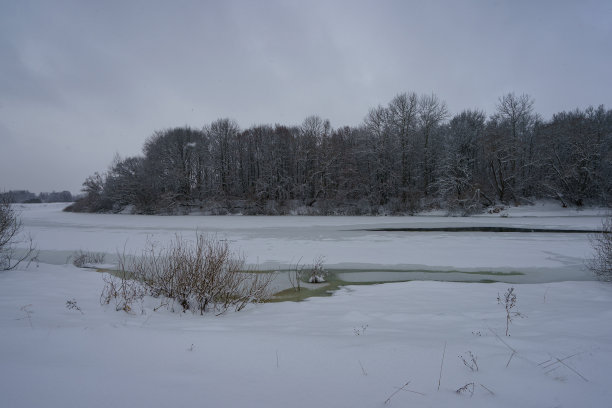 俄罗斯冬季景观在阴天，河流被冰雪覆盖图片下载
