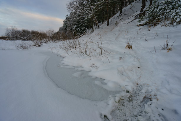 俄罗斯冬季景观在阴天，河流被冰雪覆盖图片下载
